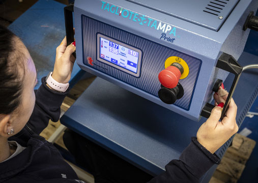 Un'operaia avvia la stampante a sublimazione per stampare un logo su una polo